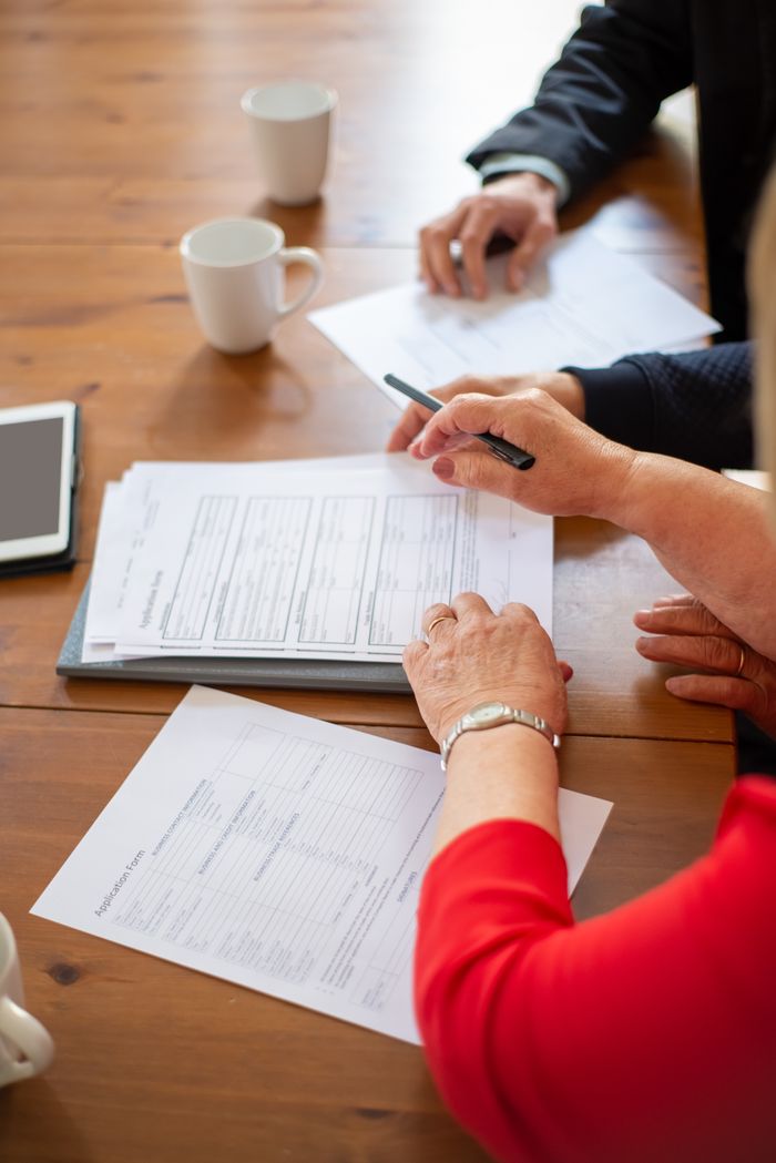 Crafting Captivating Headlines: Your awesome post title goes here Business professionals reviewing contracts at a table, accompanied by coffee and a digital tablet.